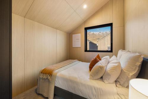 a bedroom with a bed with white pillows and a window at Kawarau Villa, Queenstown in Queenstown