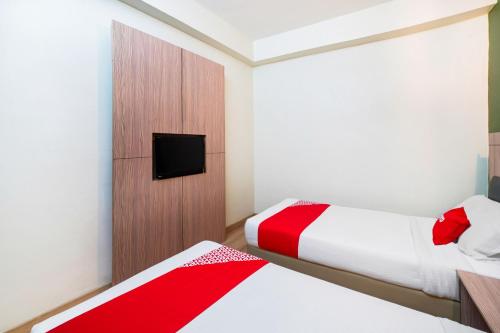 a bedroom with two beds and a tv on a wall at Dancenter Seremban Near Gateway Mall Formerly Sri Mutiara Hotel in Seremban