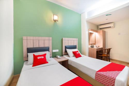 two beds in a room with red and white pillows at Dancenter Seremban Near Gateway Mall Formerly Sri Mutiara Hotel in Seremban