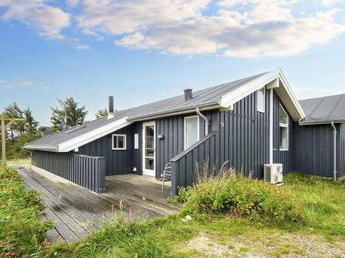 a blue house with a wooden deck in front of it at 10 person holiday home in Harboøre-By Traum in Harboør