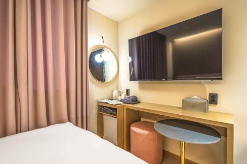 a hotel room with a desk with a bed and a television at Yongin IPPDA Petite in Yongin