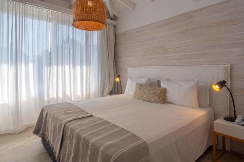 a bedroom with a white bed with a large window at Anastasio Hotel & Beach Club in José Ignacio