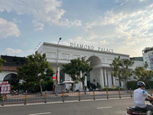 a man riding a scooter in front of the diamond palace at The Western Capital Apartment, Eric House in Ho Chi Minh City