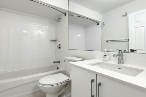 a white bathroom with a toilet and a sink at Hotel Airport View at Delhi Airport by Global Group in New Delhi