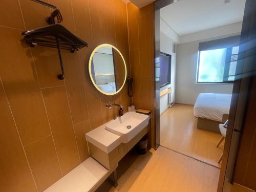 a bathroom with a sink and a mirror and a bed at JI Hotel Beijing Qianmen Courtyard in Beijing