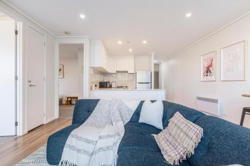 a living room with a blue couch and a kitchen at ☆of Southbank☆Light filled apartment☆HUGE private terrace with city views☆Parking☆Pool☆Gym☆WiFi in Melbourne