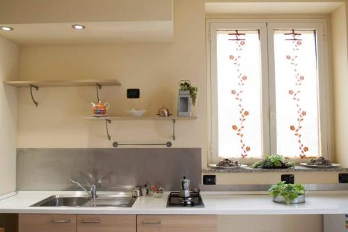 a kitchen with a sink and two windows in it at Casa Vacanze Bellovello in Barbaresco