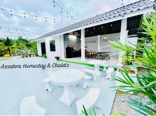 a white house with a white table and chairs at Azzahra Homestay & Chalet in Temerloh