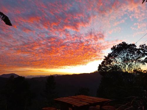 a sunset in the mountains with a picnic table at Ella Shia Cabana in Badulla