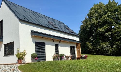 a white building with a black roof on a grass field at Srnčí vrch in Batňovice