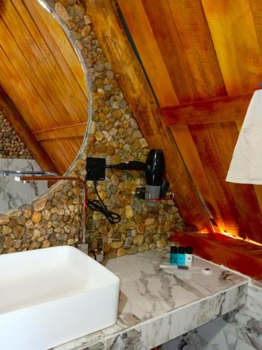 a bathroom with a sink and a stone wall at Ella Shia Cabana in Badulla