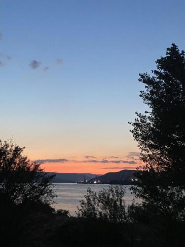 a sunset over a body of water with trees at La Sirena in Kladovo