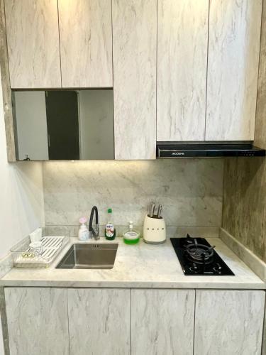 a kitchen with a sink and a stove at 2BR Peaceful & Cozy Family Condo in Jakarta