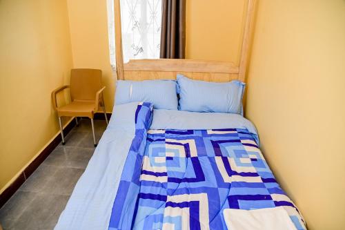 a bedroom with a bed with a blue and white quilt at Perudas Place in Kampala