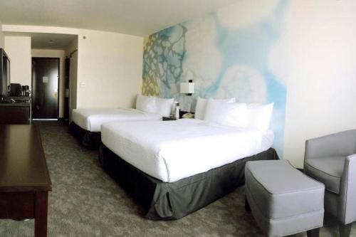 a hotel room with two beds and a chair at Courtyard by Marriott San Luis Potosi in San Luis Potosí