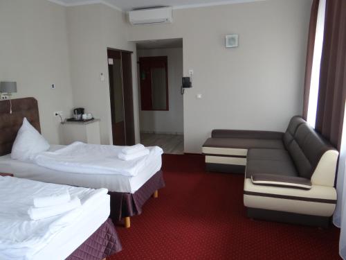 a hotel room with two beds and a couch at Hotel Relax in Słubice