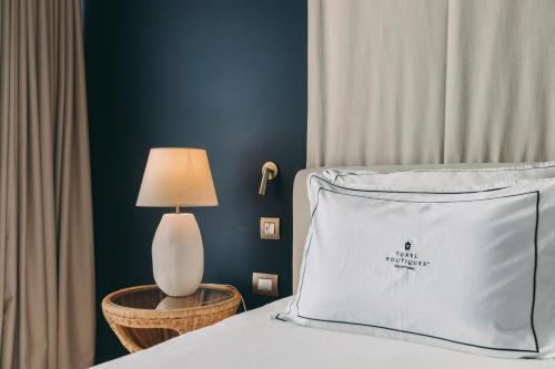 a bed with a white pillow and a lamp on a table at Torel Terra Brava in Angra do Heroísmo