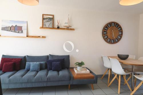 a living room with a couch and a table and a clock at COC - La Brise Marine in Wissant