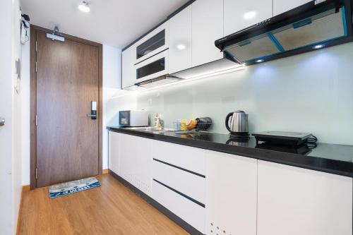 a kitchen with white cabinets and a black counter top at Soho Apartment Central in District 1 in Ho Chi Minh City