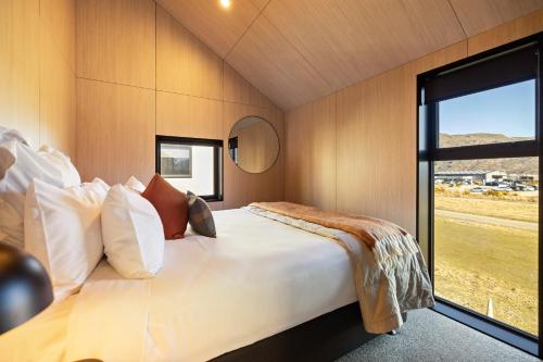 een slaapkamer met een groot bed met een groot raam bij Tahuna Luxury Villa Queenstown in Queenstown
