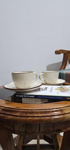 a table with two tea cups and books on it at The Hill Crest, Fagu in Shimla