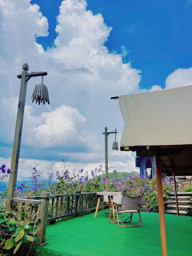 a table and chairs on a balcony with flowers at Cloud9 & Cloud View Glamping in Da Lat