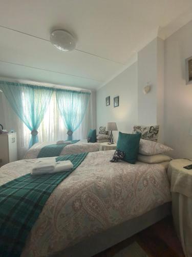 a bedroom with two beds with blue drapes at At Whale-Phin Guest House in Reebok
