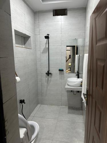 a bathroom with a shower and a toilet and a sink at Kami House in Multan