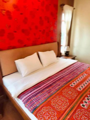 a bedroom with a bed with a red wall at Plumeriahome near Chiangmai Airport in Chiang Mai