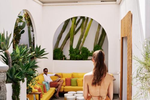 a woman in a bikini looking at a man sitting on a couch in a room at Myconian Korali Relais & Chateaux in Mýkonos City
