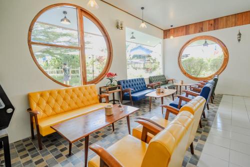 a restaurant with couches and tables and windows at บ้านสวนลุงหวัด พังงา in Takua Thung