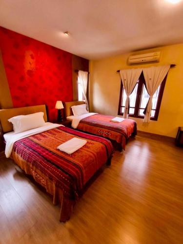 two beds in a hotel room with red walls at Plumeriahome near Chiangmai Airport in Chiang Mai
