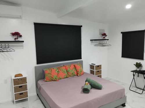 a bedroom with a bed and two flat screens at Sharnyta's Studio Aitutaki in Amuri