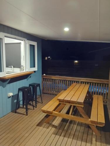 a picnic table and stools on a deck at Sharnyta's Studio Aitutaki in Amuri