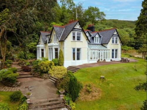 a large white house with a grass yard at Camus House, Lochside Guest House in Onich