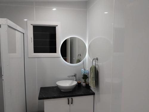 a white bathroom with a sink and a mirror at Sharnyta's Studio Aitutaki in Amuri