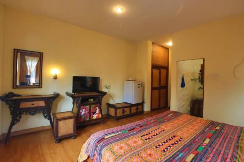 a bedroom with a bed and a television and a table at Plumeriahome near Chiangmai Airport in Chiang Mai