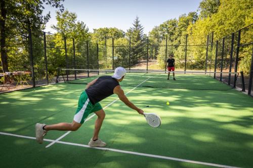 two people playing tennis on a tennis court at Huttopia de Wattwiller in Wattwiller