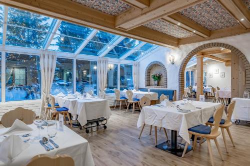 a restaurant with white tables and chairs and windows at Turmhotel Victoria Davos in Davos