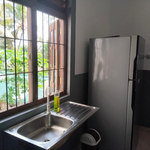 a kitchen with a sink and a refrigerator at Tharul Home in Bentota