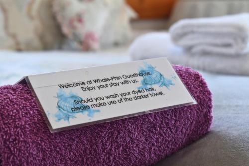 a sign sitting on top of a purple towel at At Whale-Phin Guest House in Reebok
