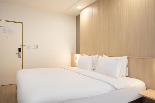 a bedroom with a large white bed with white pillows at Diya Hotel Bangkok in Amphoe Phra Khanong