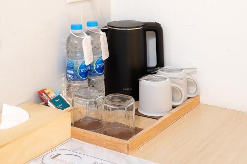 a wooden tray with water bottles and glasses on a counter at Diya Hotel Bangkok in Amphoe Phra Khanong