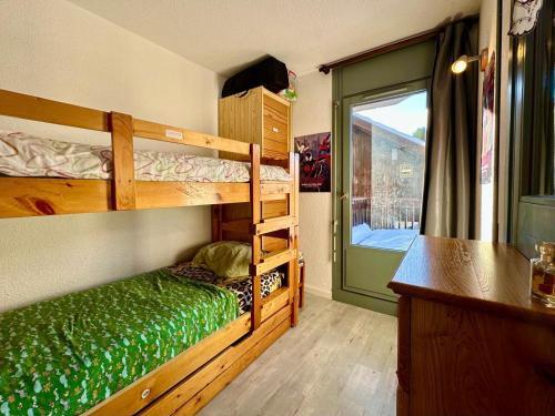 Un dormitorio con dos literas y una ventana. en Edelweiss Résidence plein centre de la station rez de chaussée 50 m des navettes gratuites belle terrasse et grand parking privé en sous sol, en Les Carroz d'Araches