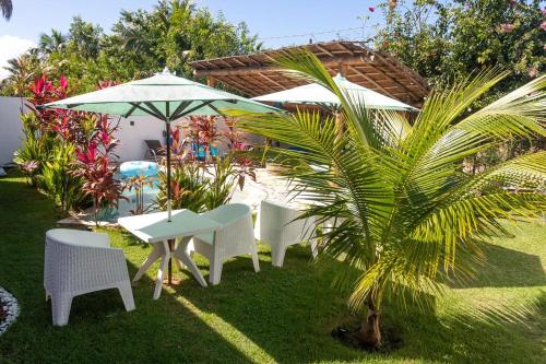 a table and chairs and an umbrella and a palm tree at Mar Turquesa Eco Pousada in Maragogi