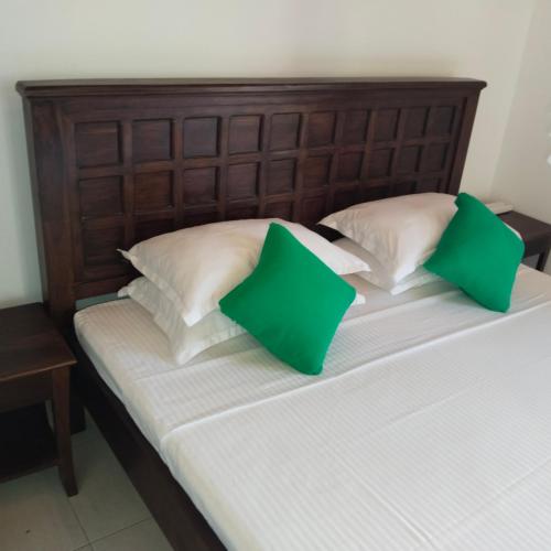 a bed with two green pillows on top of it at Tharul Home in Bentota