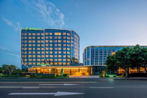 a large building with lights on in front of a street at Holiday Inn Fuzhou Exhibition Center in Fuzhou