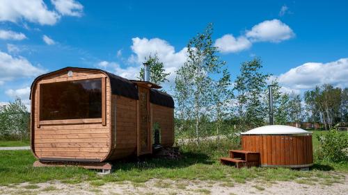 a wooden trailer sitting in the grass next to a barrel at Pokoje Gościnne Butryny in Butryny