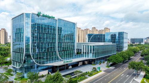 a large glass building in a city with a street at Holiday Inn Fuzhou Exhibition Center in Fuzhou