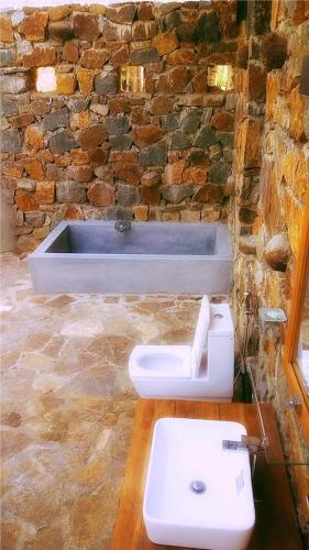 a stone bathroom with a sink and a bath tub at Kottawatta Village in Udawalawe